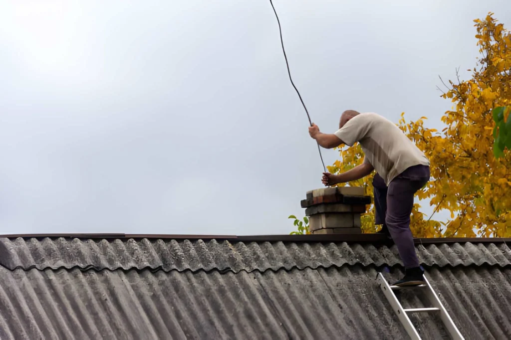 Professional Chimney Sweep removing soot and creosote from a residential fireplace system.